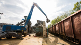 Bagger verlädt Eisenschrott in Waggons 