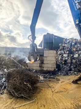 Eine brennende Batterie wird aus dem Mischschrott geborgen. 